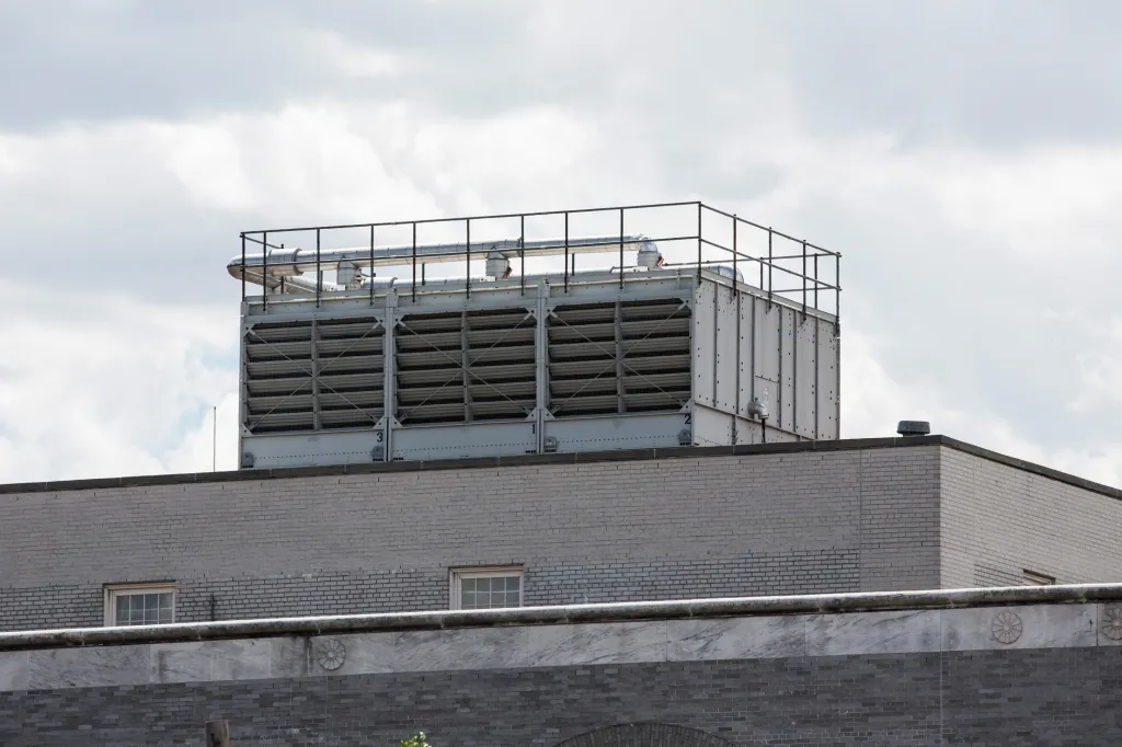 Cooling tower on the roof of a brick building.