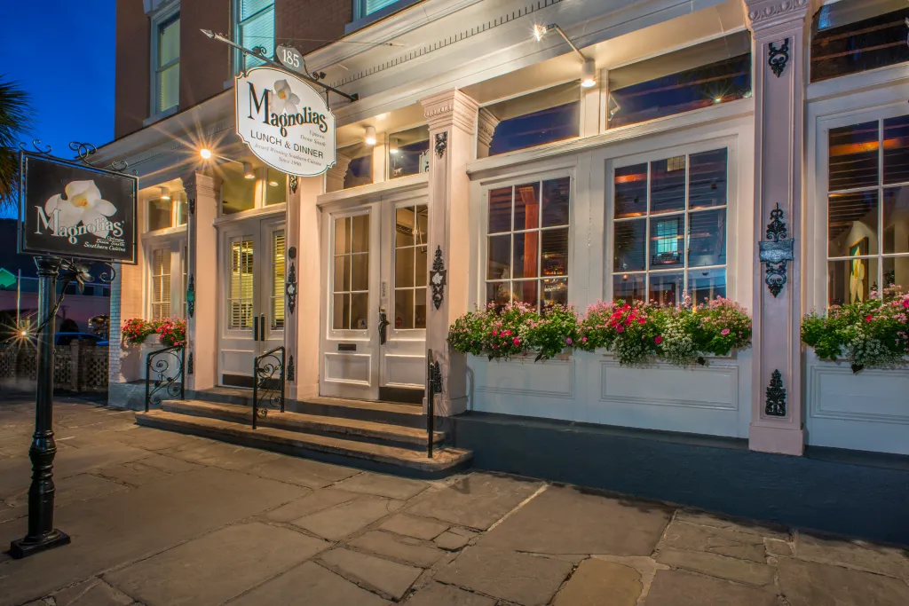 The illuminated entrance of Magnolias restaurant with flower boxes under the windows.