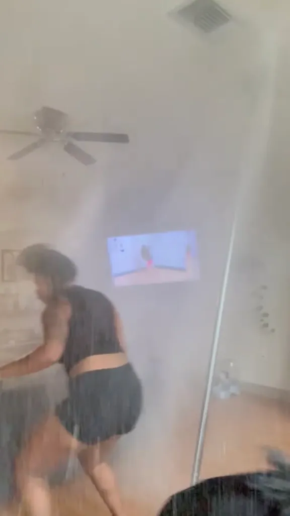 A person exercising in a room with water spraying everywhere.