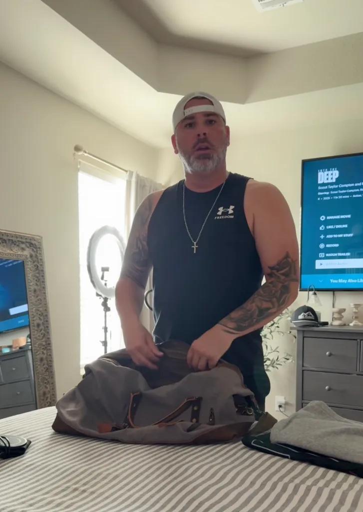 A man packing a duffel bag on a bed.
