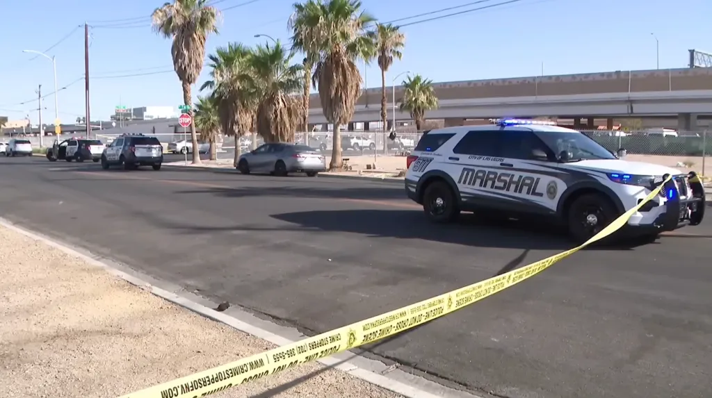 A "City of Las Vegas Marshal" vehicle and other police cars block a street with crime scene tape.