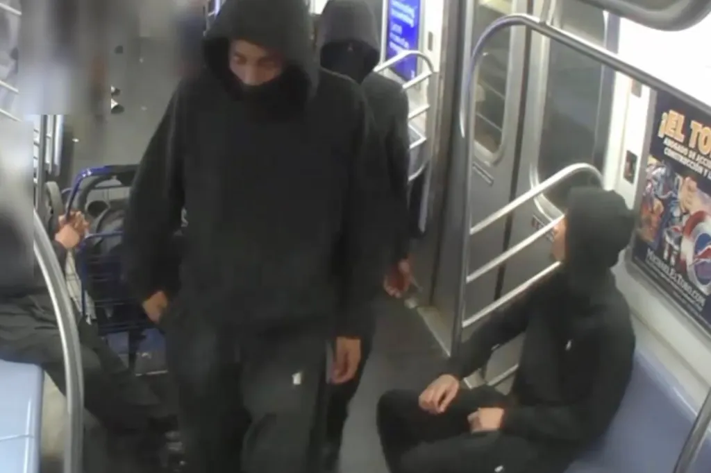 Three individuals in black hoodies inside a subway car.