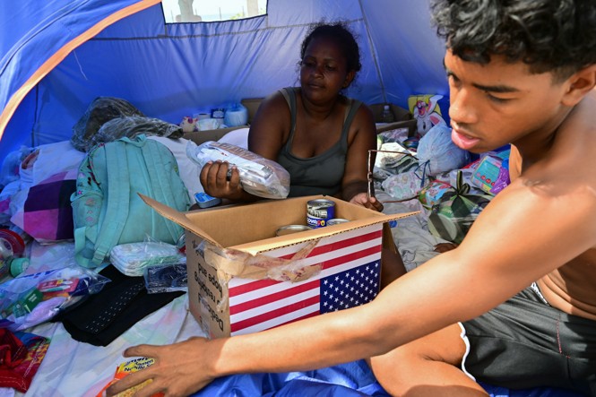 People look at food from a box with an image of the American flag