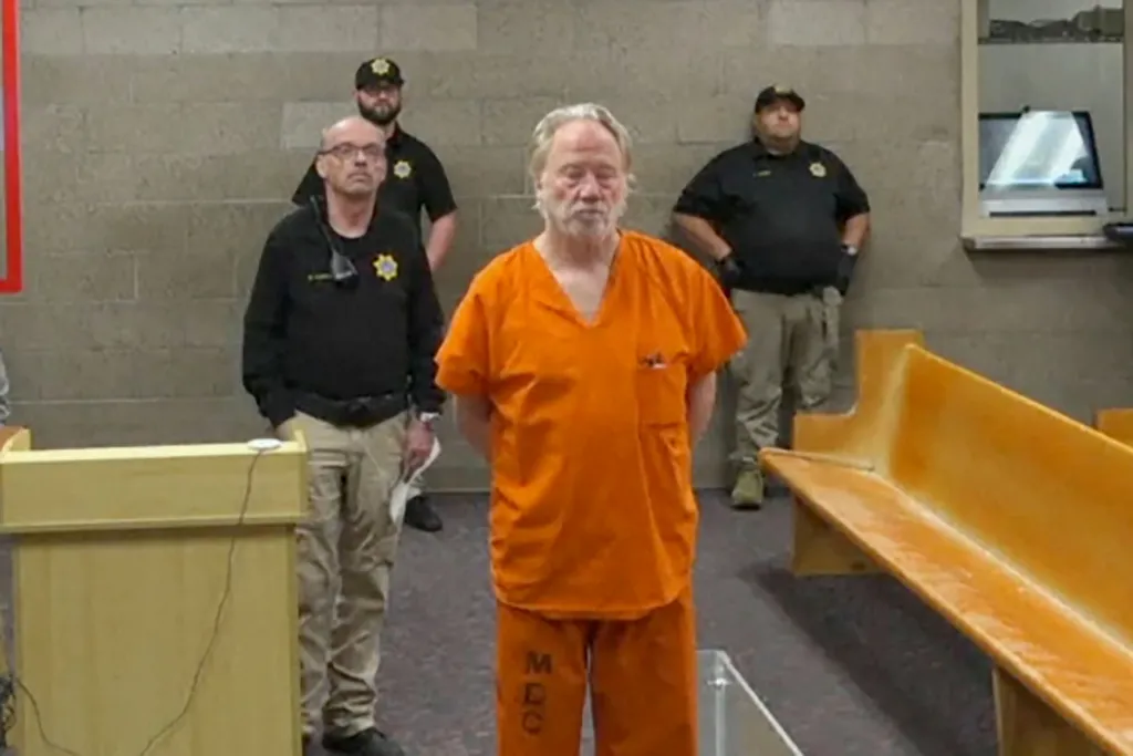 Actor-director Timothy Busfield in an orange jumpsuit, flanked by two officers, appears in court on child sexual abuse charges.