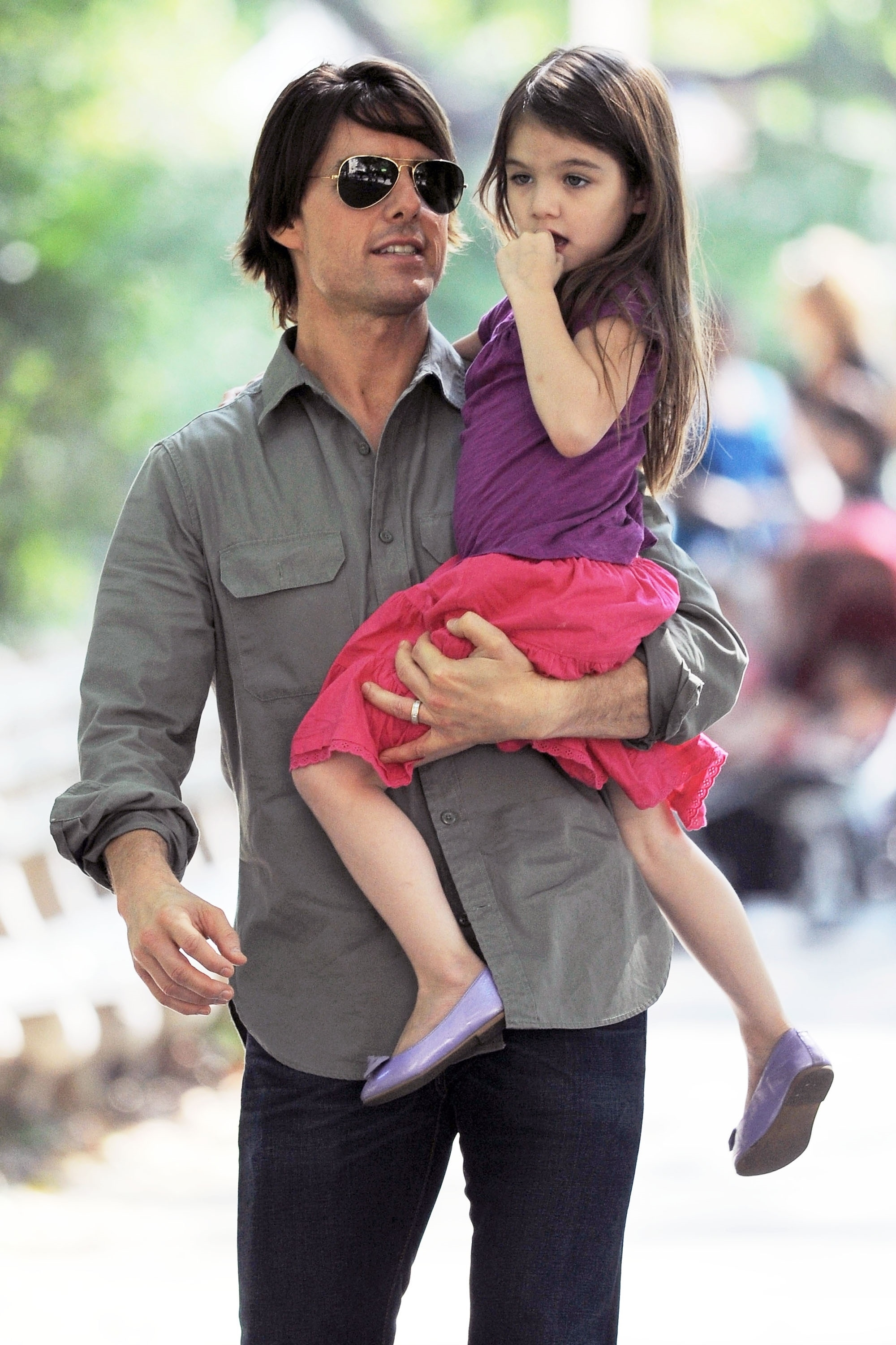 Tom Cruise holding his daughter, Suri, who is wearing a pink dress.