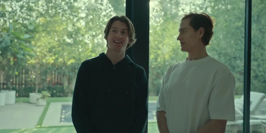 Talmage Johnson and Bryan Johnson standing indoors with a view of greenery outside.