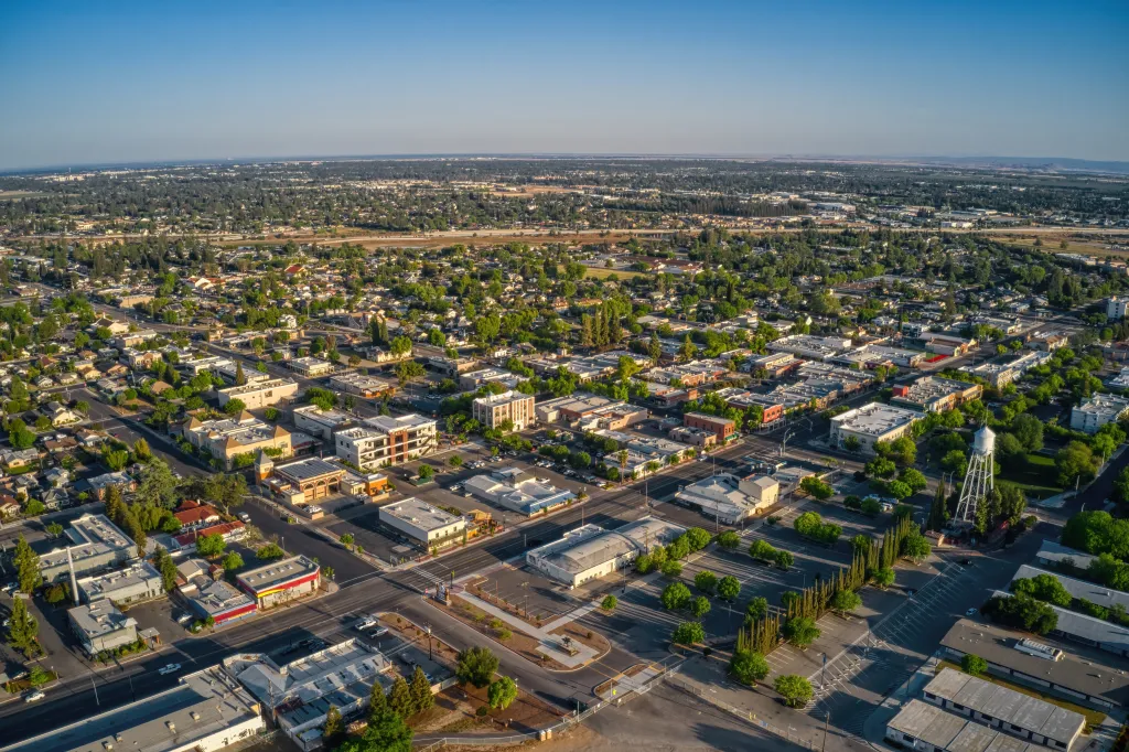 Aerial view of the Fresno suburb of Clovis, California, with numerous buildings and trees under a clear blue sky.