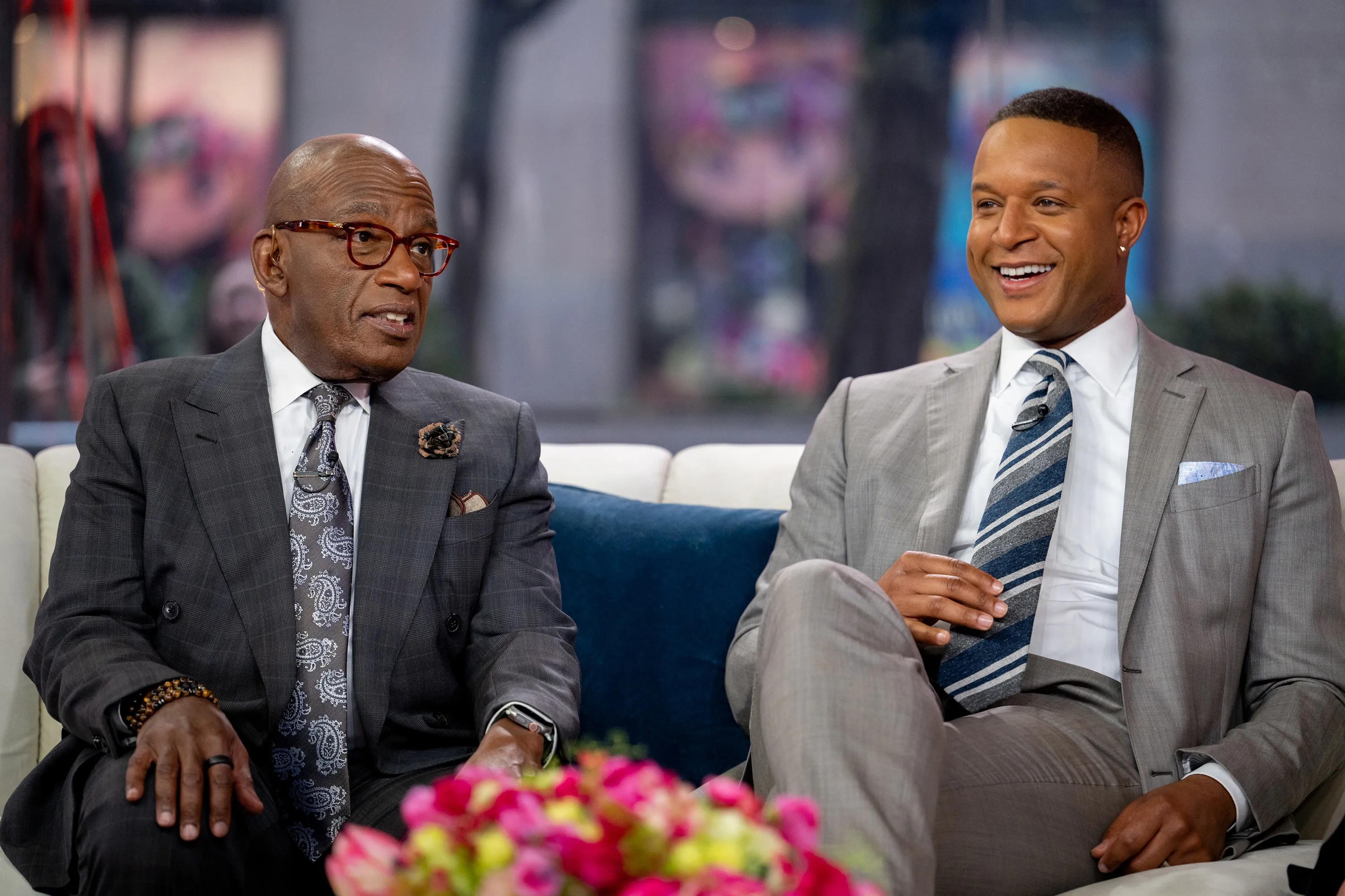 Al Roker and Craig Melvin sitting together on a couch, with Roker looking left and Melvin smiling to the right.