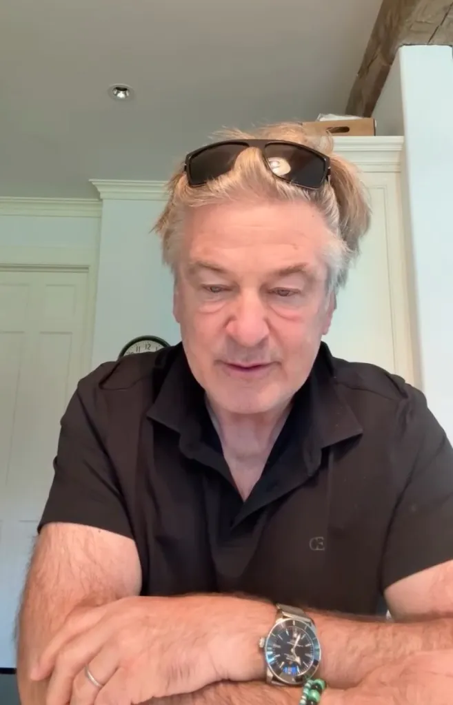 Actor Alec Baldwin wearing a black polo shirt and sunglasses on his head.