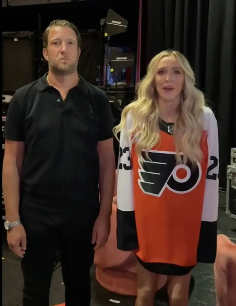 Alex Cooper, in an oversized sports top in black, orange and white, and Dave Portnoy, in a black top and black pants.