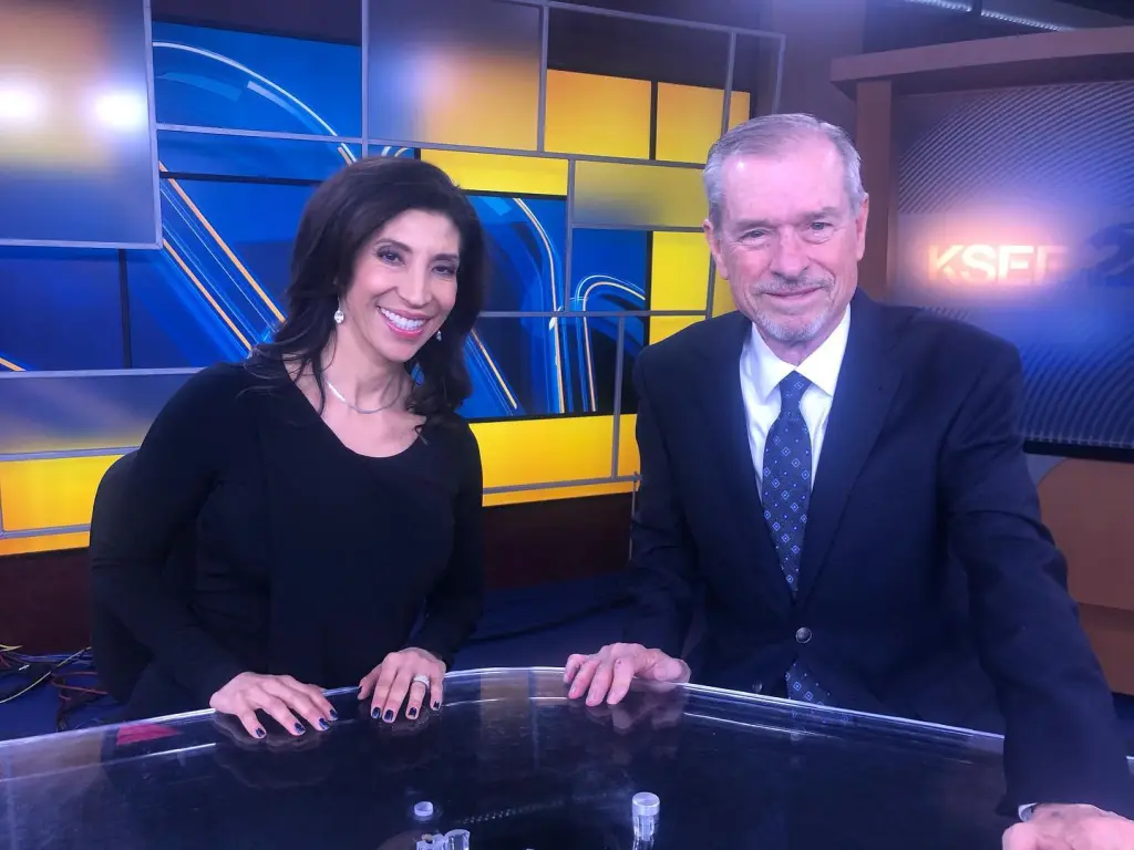 Alex Delgado with a male colleague at a news desk.