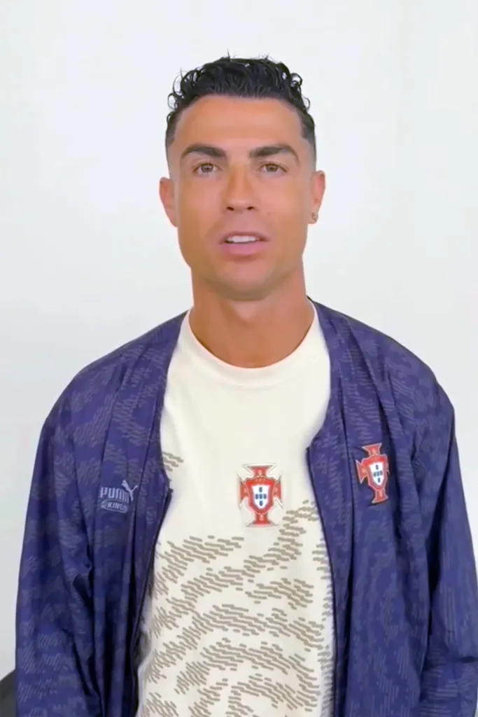 Headshot of Cristiano Ronaldo in a blue jacket over a white shirt with a Portuguese crest.