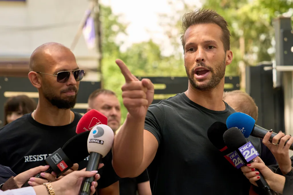 Andrew Tate, left, watches his brother Tristan speak, outside a police station in Voluntari, Romania, May 21, 2025.