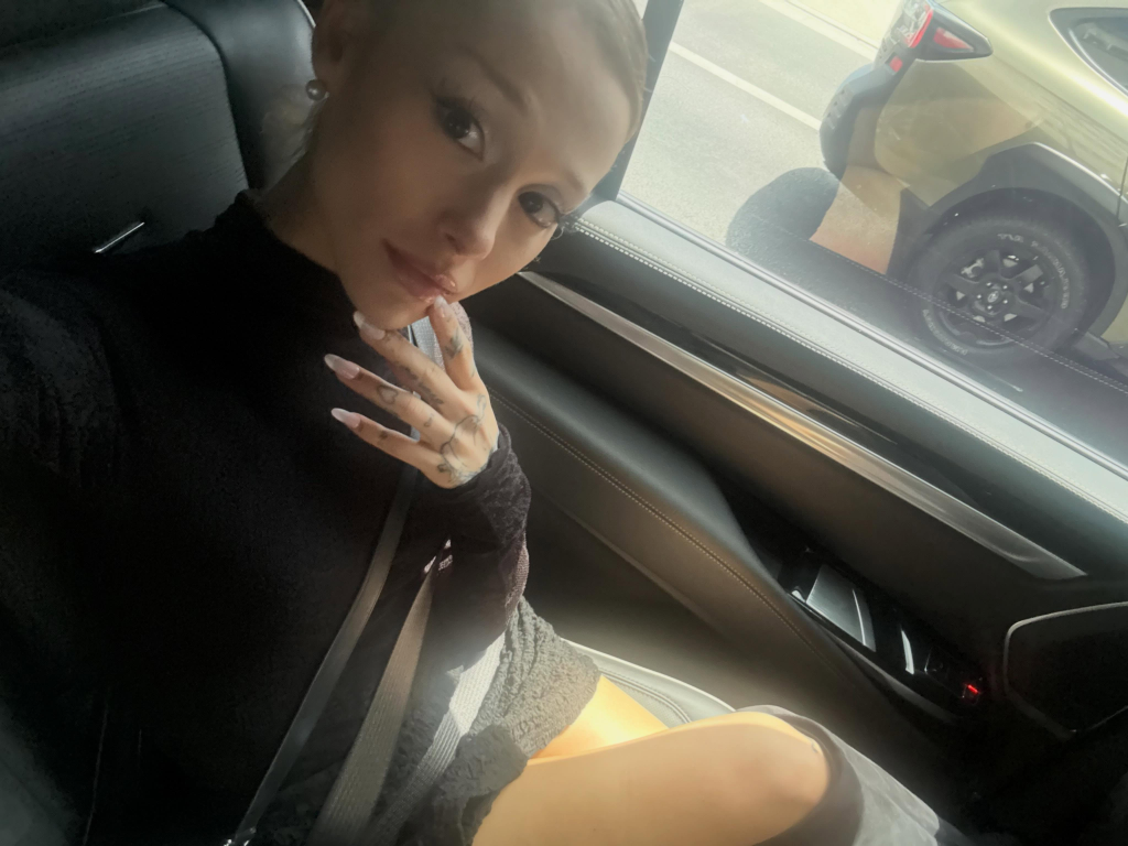 Ariana Grande takes a selfie in the backseat of a car.