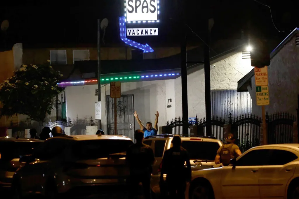 Nighttime scene of an arrest outside a motel with a "SPAS VACANCY" sign.