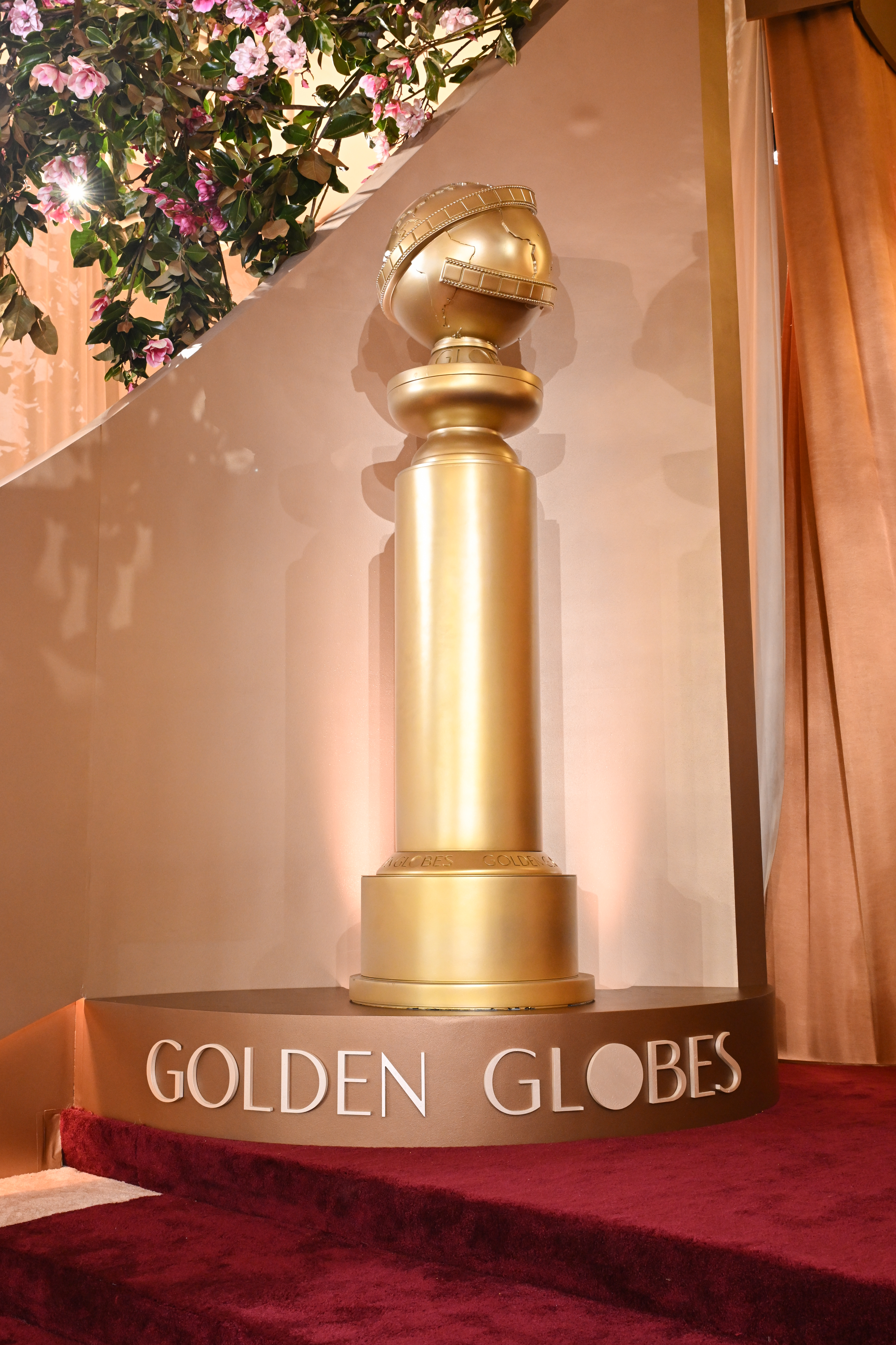 Golden Globes trophy on a red carpet with "Golden Globes" spelled out at the base.