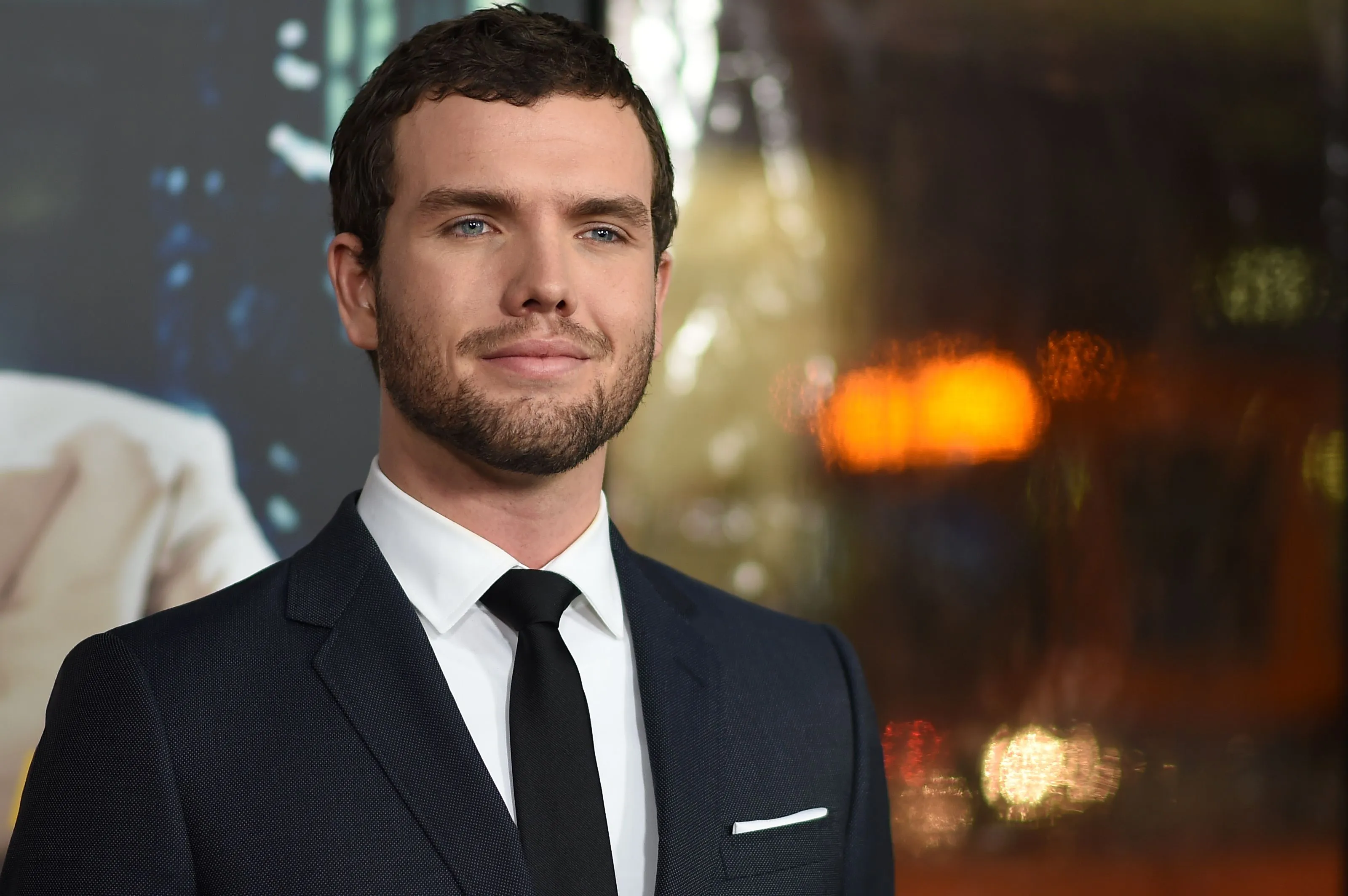Austin Swift in a suit and tie, smiling faintly at the premiere of "Live By Night."