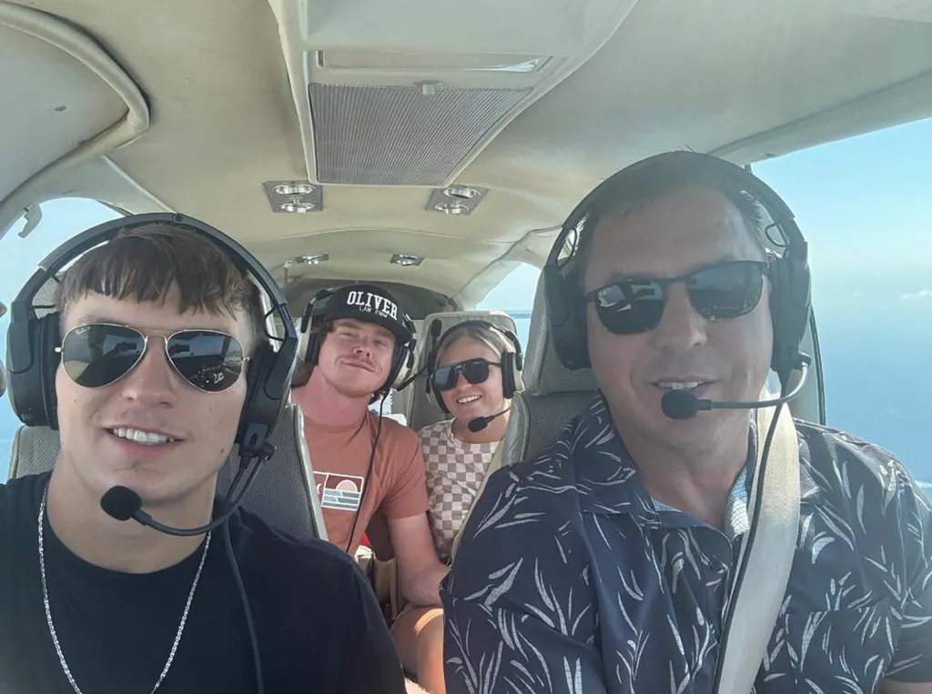 Four people in an airplane wearing headphones with microphones.