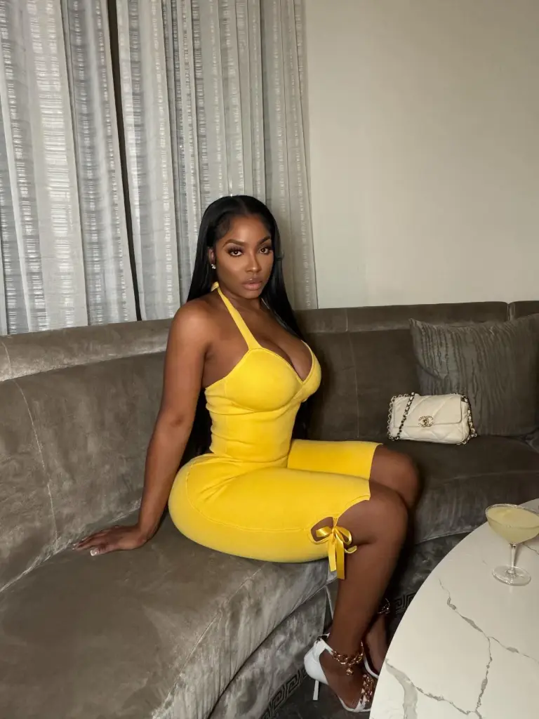 Ayesha Howard in a yellow romper on a couch.