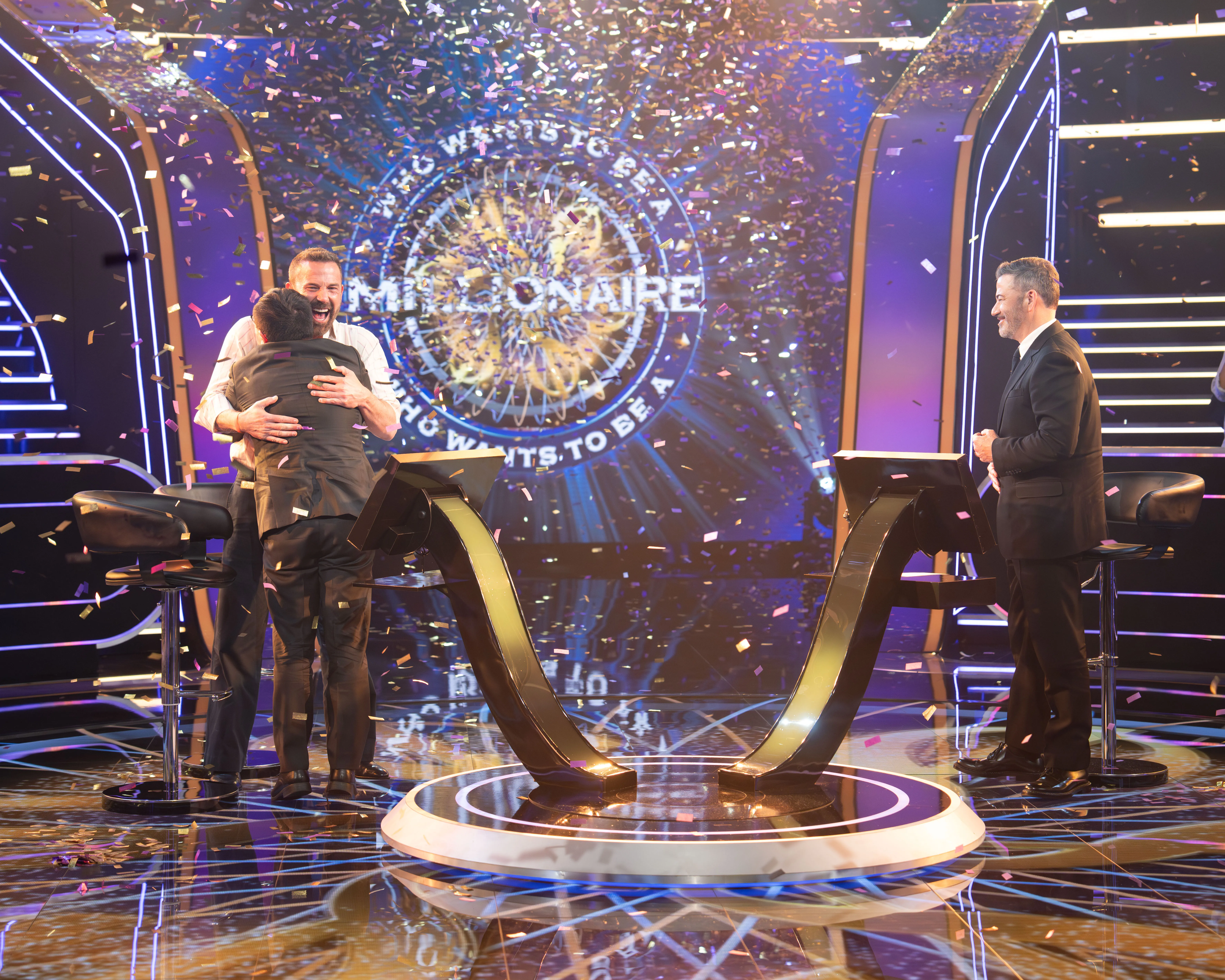 Ben Affleck hugs Jamie Ding as confetti falls on the set of "Who Wants to Be a Millionaire," with Jimmy Kimmel standing to the right.