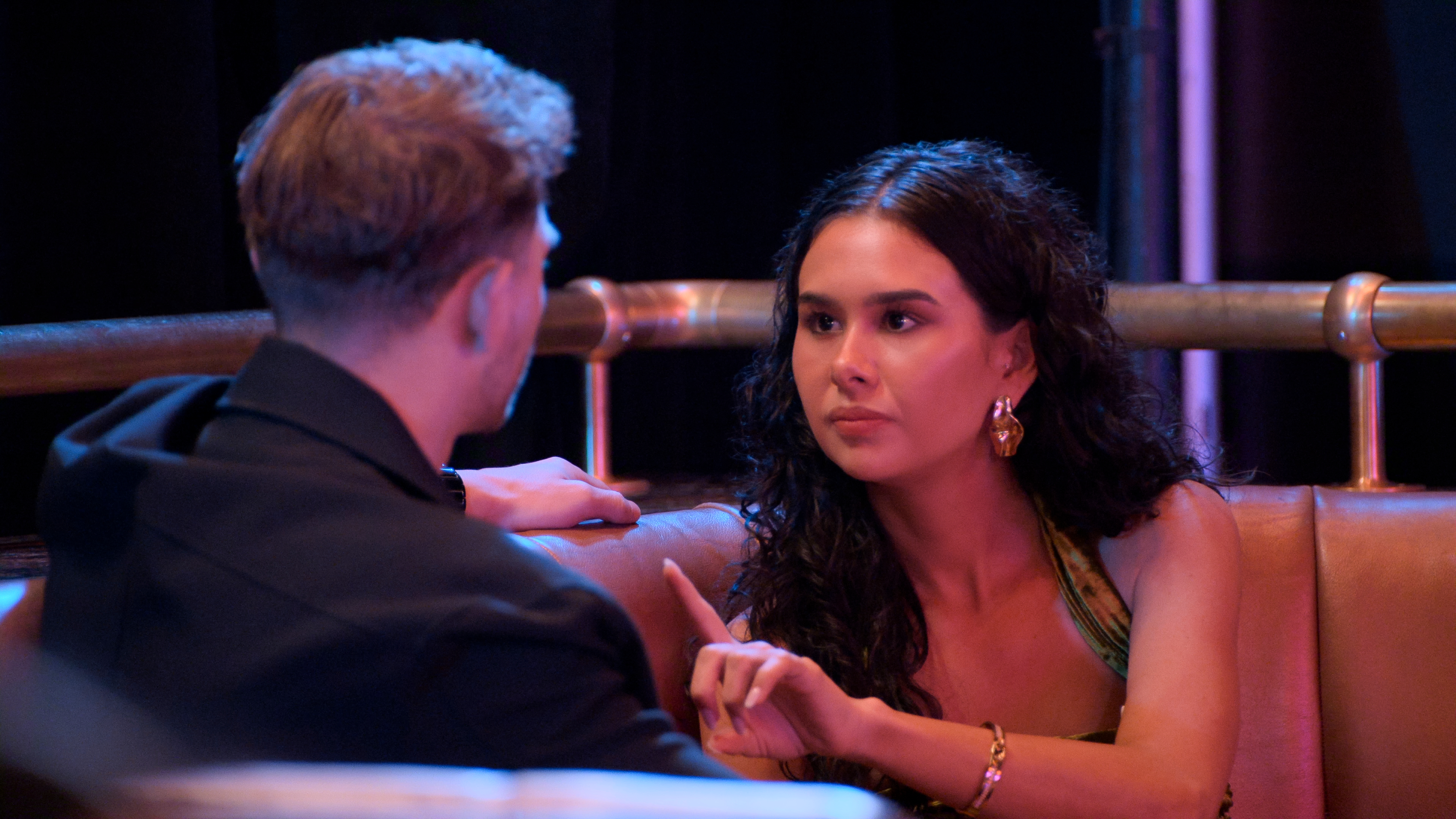 Blake Robertson and Hayley Hendrich sit facing each other on a brown leather booth.