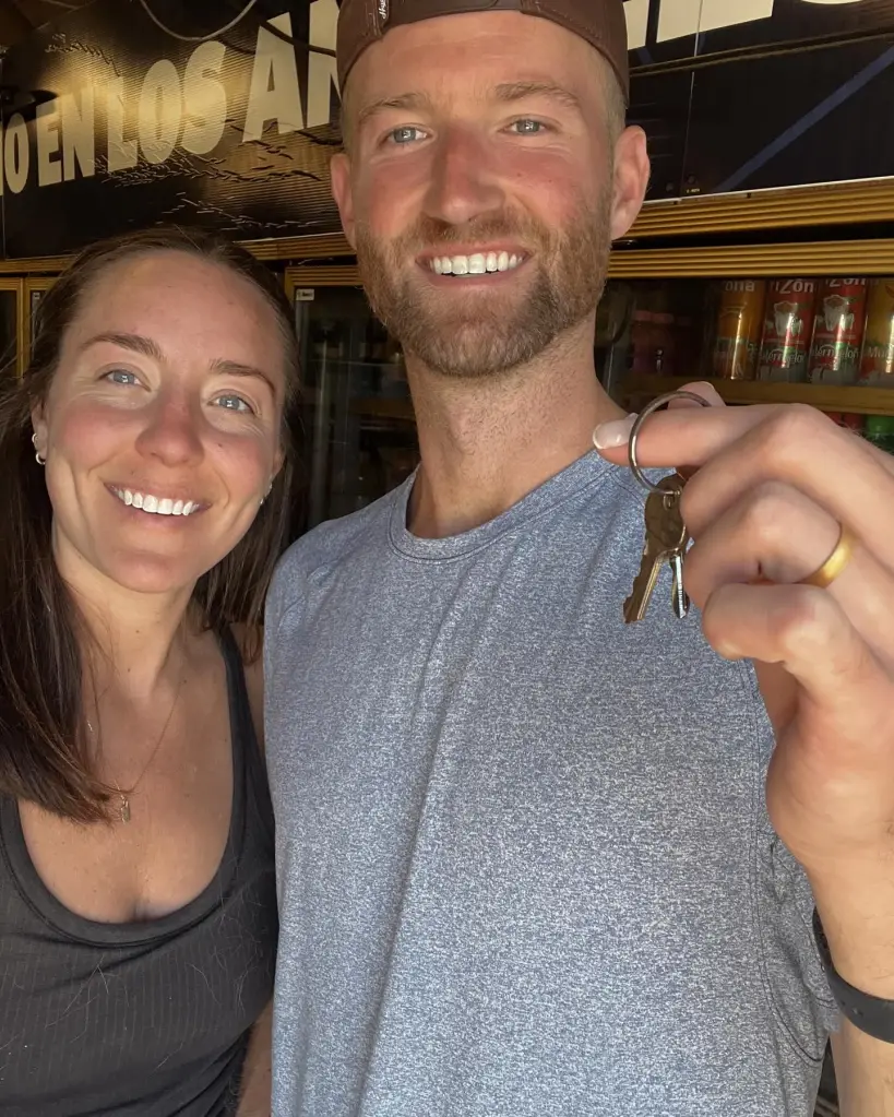 A smiling man holding up keys next to a smiling woman.