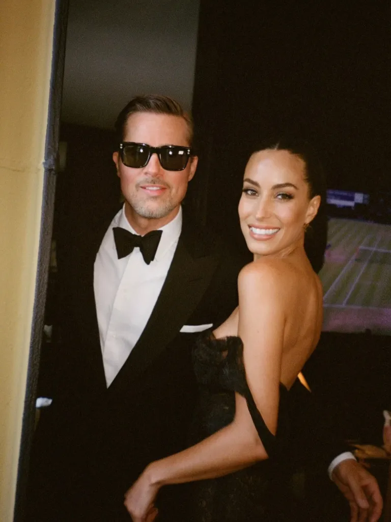 Brad Pitt in sunglasses and Ines de Ramon smiling at a wedding.