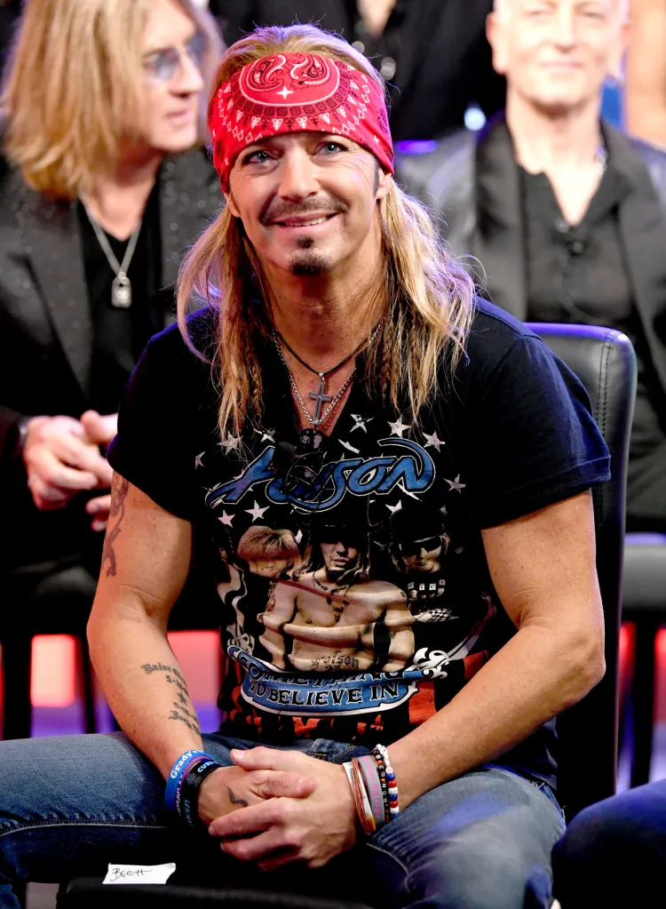 Bret Michaels smiles while wearing a red bandana and a black "Poison" t-shirt.