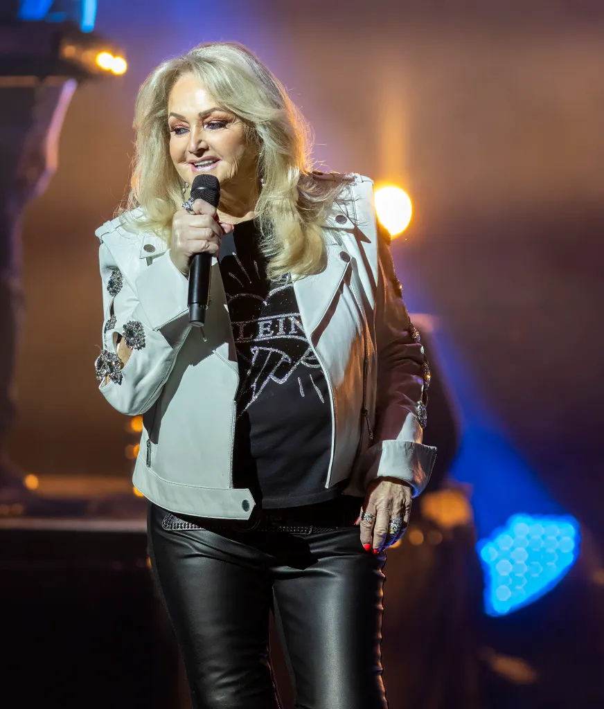 British singer Bonnie Tyler performs on stage, holding a microphone.