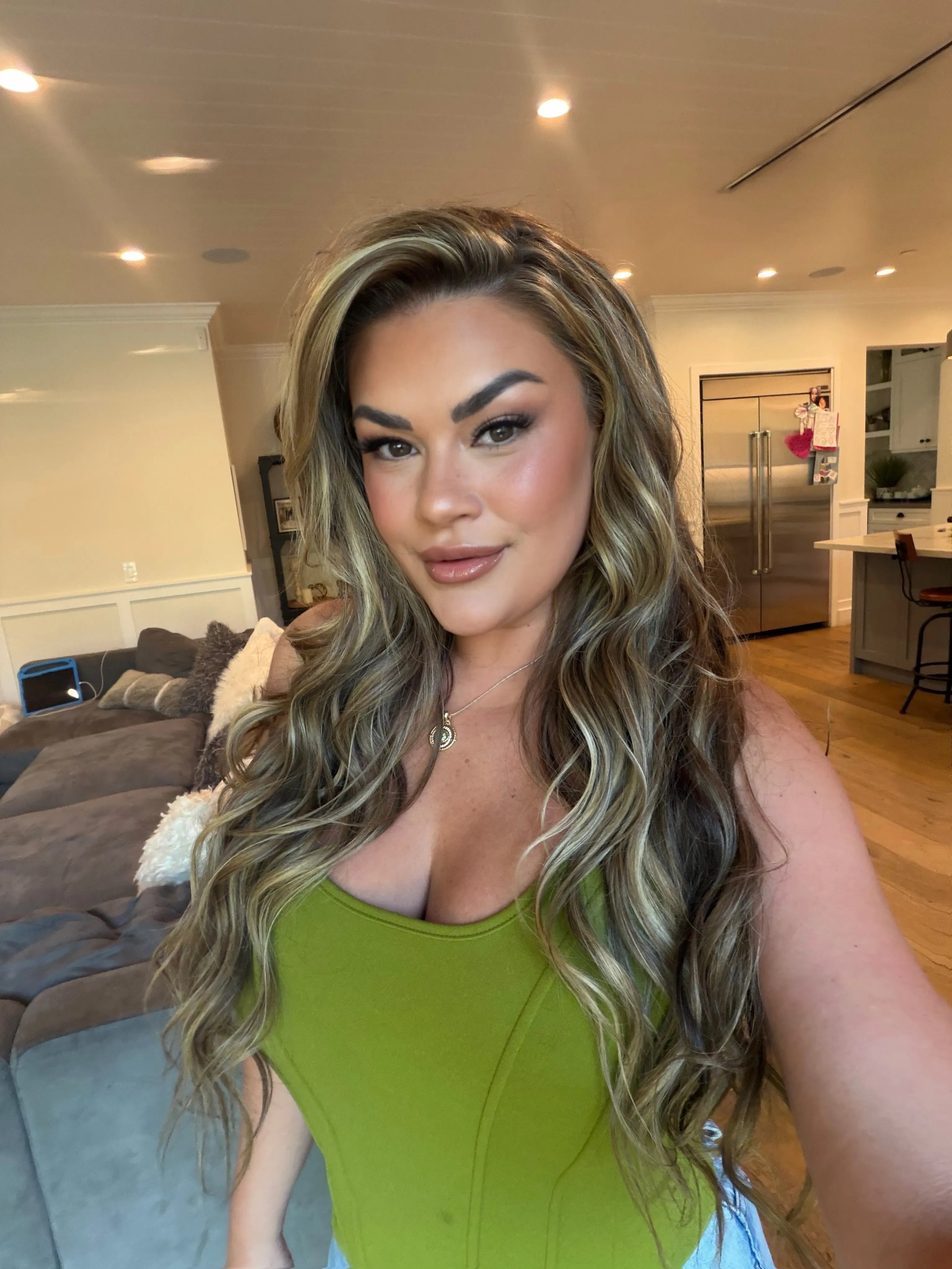 Brittany Cartwright posing for a selfie in an olive green top.