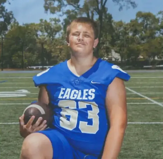 Brody Matteson in a blue football uniform with "Eagles 53" written on it, holding a football.