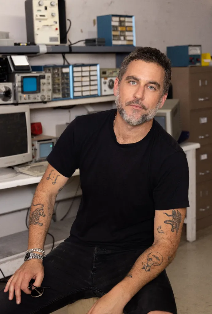 Bryn Mooser seated in a room filled with scientific equipment.