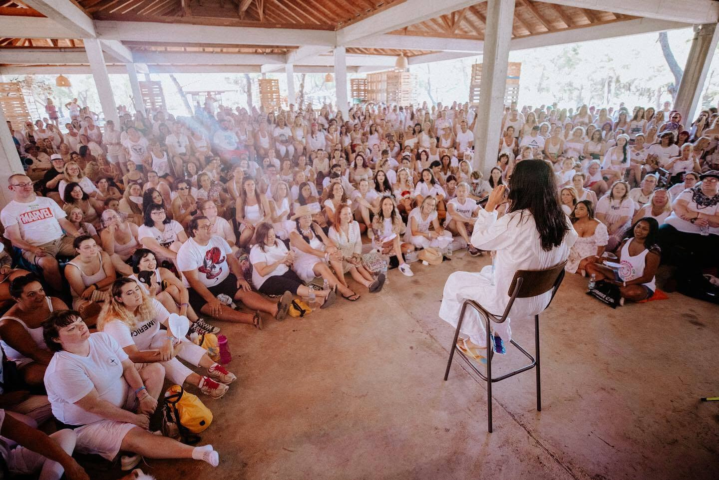 Jared Leto, dressed in white, speaks to a large group of people dressed in white at a 30 Seconds to Mars Camp Mars outing.