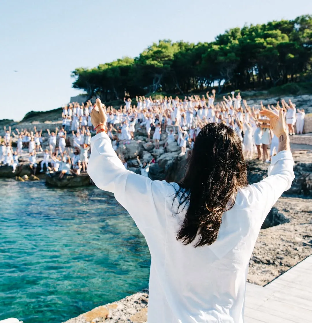 Person facing a large group in white clothing at Camp Mars on Obonjan Island, Croatia.