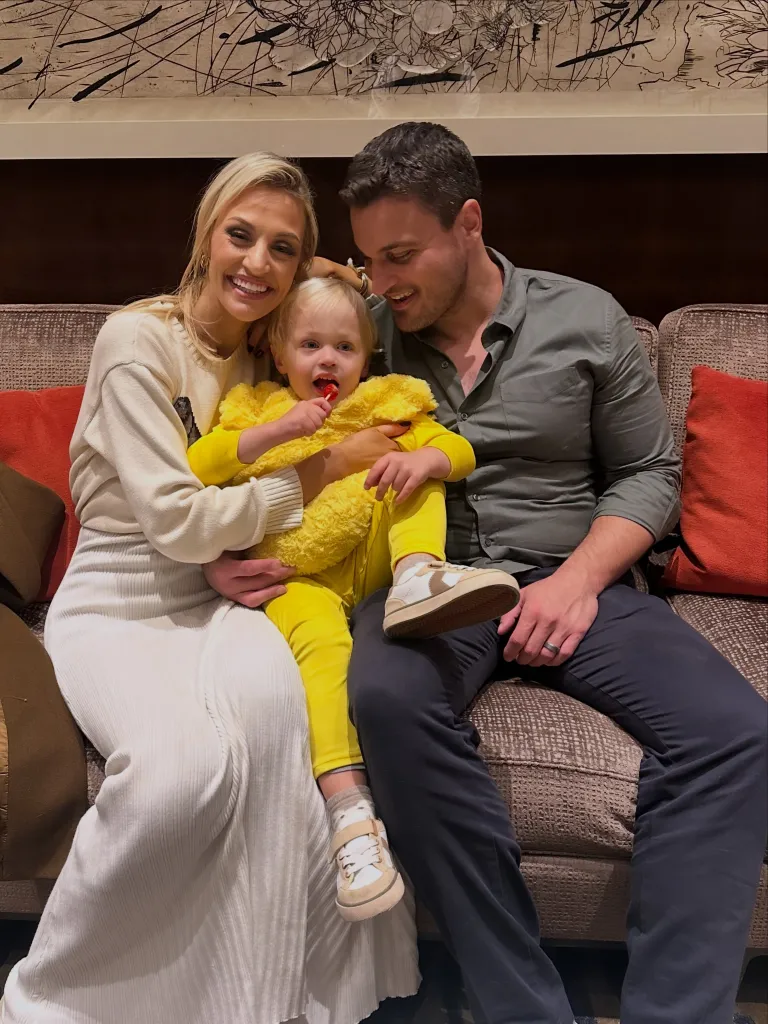 Carley Shimkus, Peter Buchignani, and their son Brock seated on a couch.