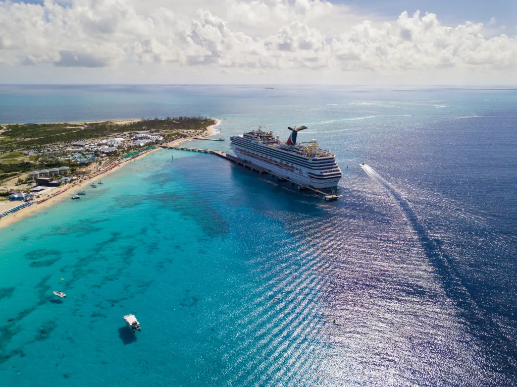 Aerial view of the Carnival Sunshine cruise ship docked in Grand Turk, Turks and Caicos, with turquoise water and a beach resort.