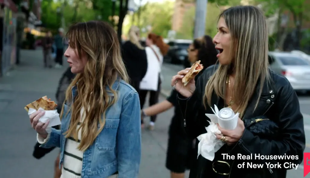 Carole Radziwill and another woman eating pizza on the street.