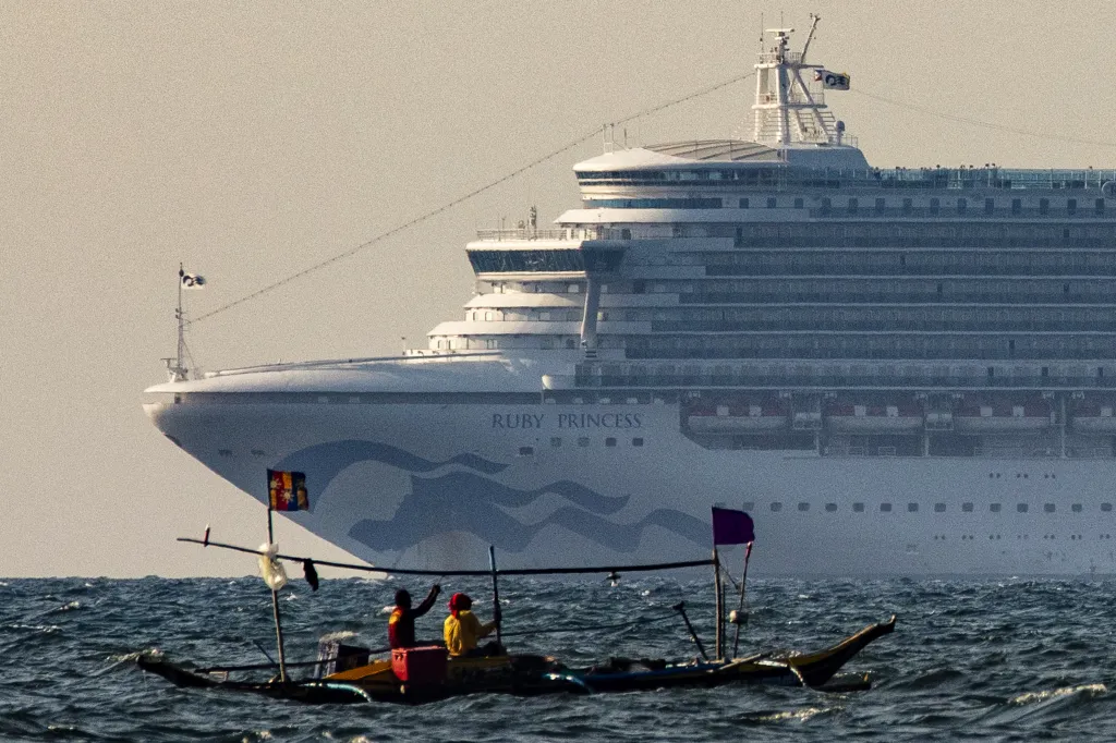 A small fishing boat with two people on board passes by the Ruby Princess cruise ship in Manila Bay.