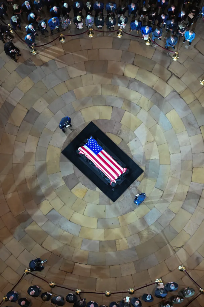 Overhead view of late U.S. Senator Lindsey Graham's casket draped with an American flag, surrounded by people in the U.S. Capitol Rotunda.