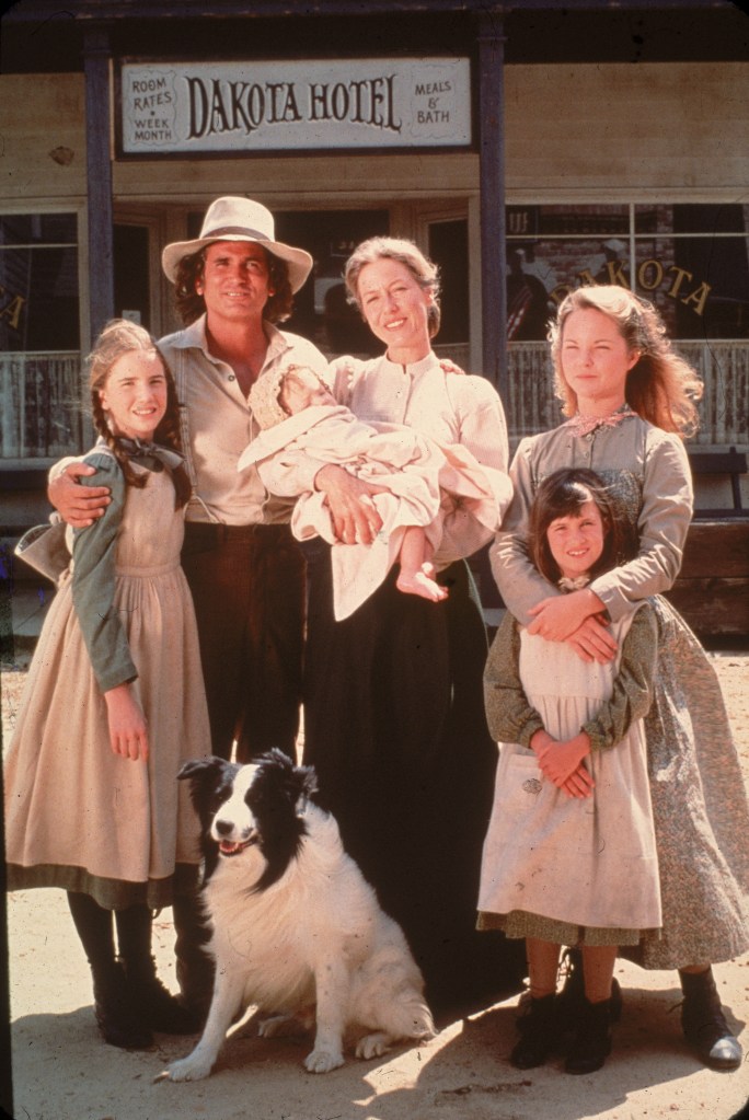 The cast of the television series "Little House on the Prairie" posing with a dog in front of the Dakota Hotel.