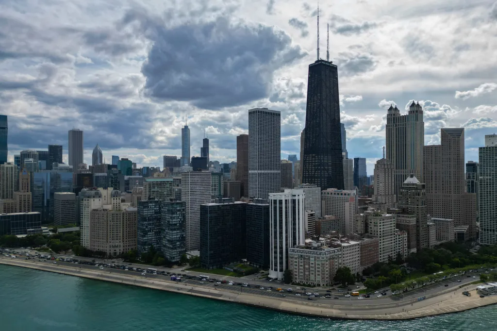 The Chicago skyline seen from above, with Lake Michigan in the foreground and a cloudy sky overhead.