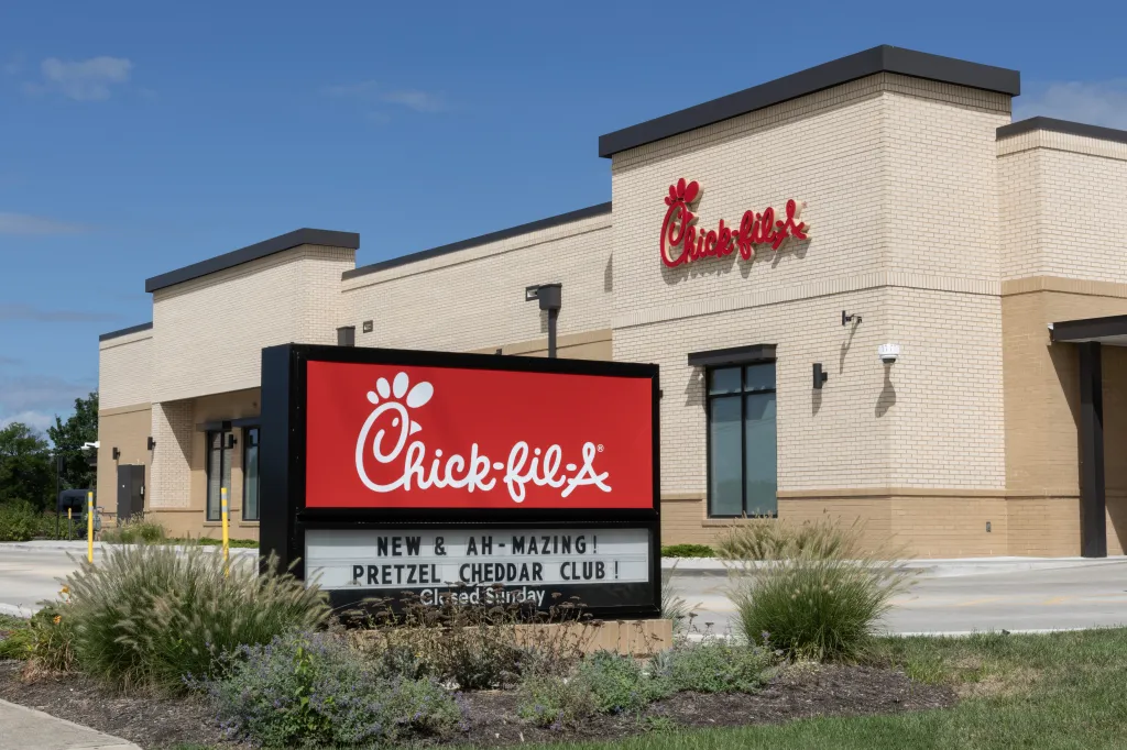 Chick-fil-A chicken restaurant with a red and white sign advertising a new pretzel cheddar club.