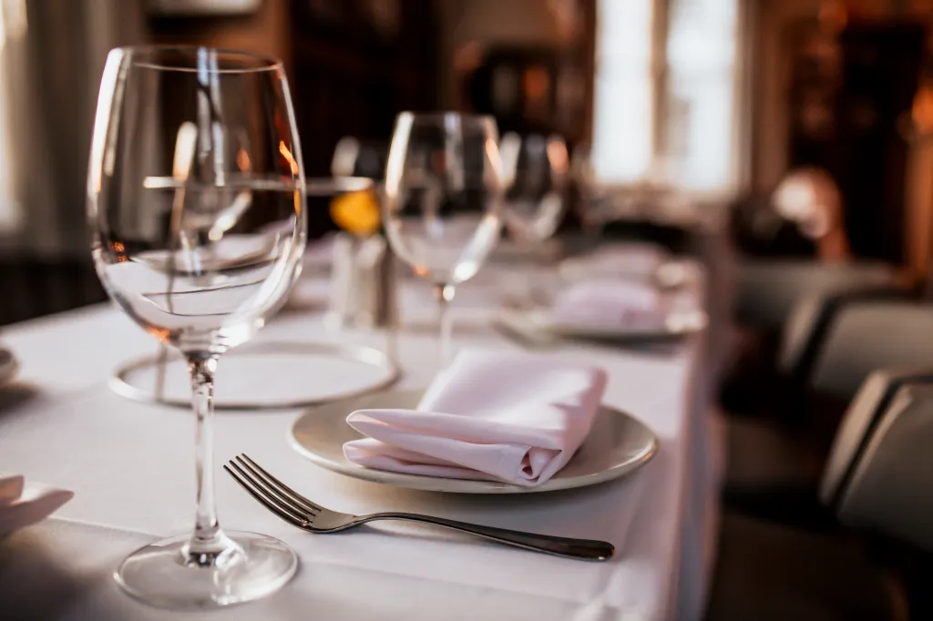 A restaurant table set with a wine glass, fork, plate, and napkin, ready for dining.
