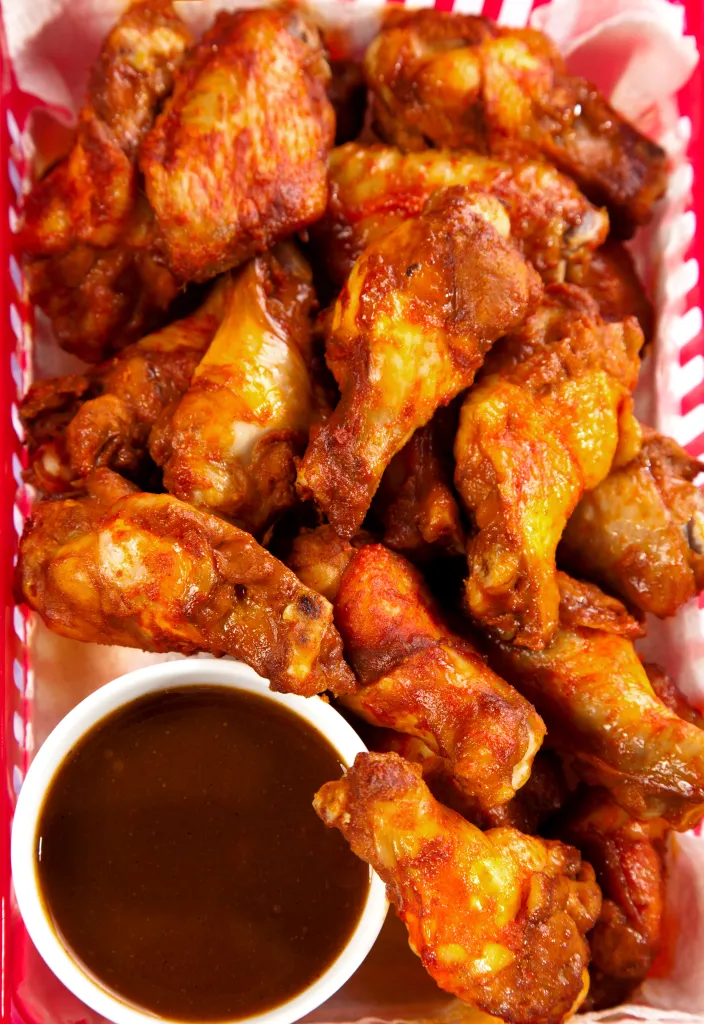 Buffalo wings with BBQ sauce in a basket.