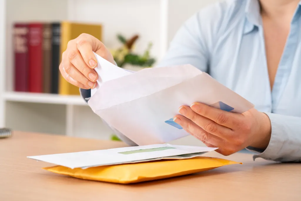 A person puts a letter into an envelope.