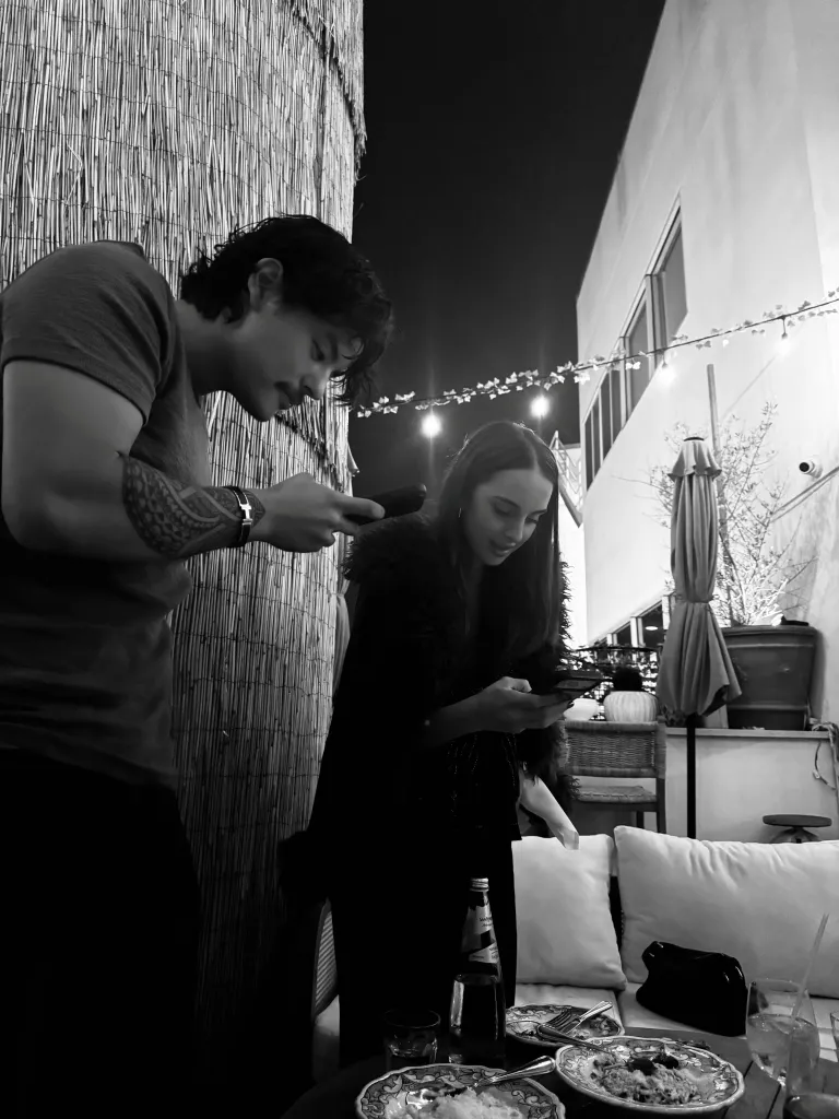 Collin Gosselin and a woman checking their phones.