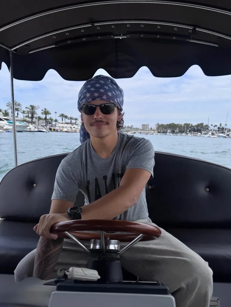 Collin Gosselin driving a boat while wearing a bandana and sunglasses.