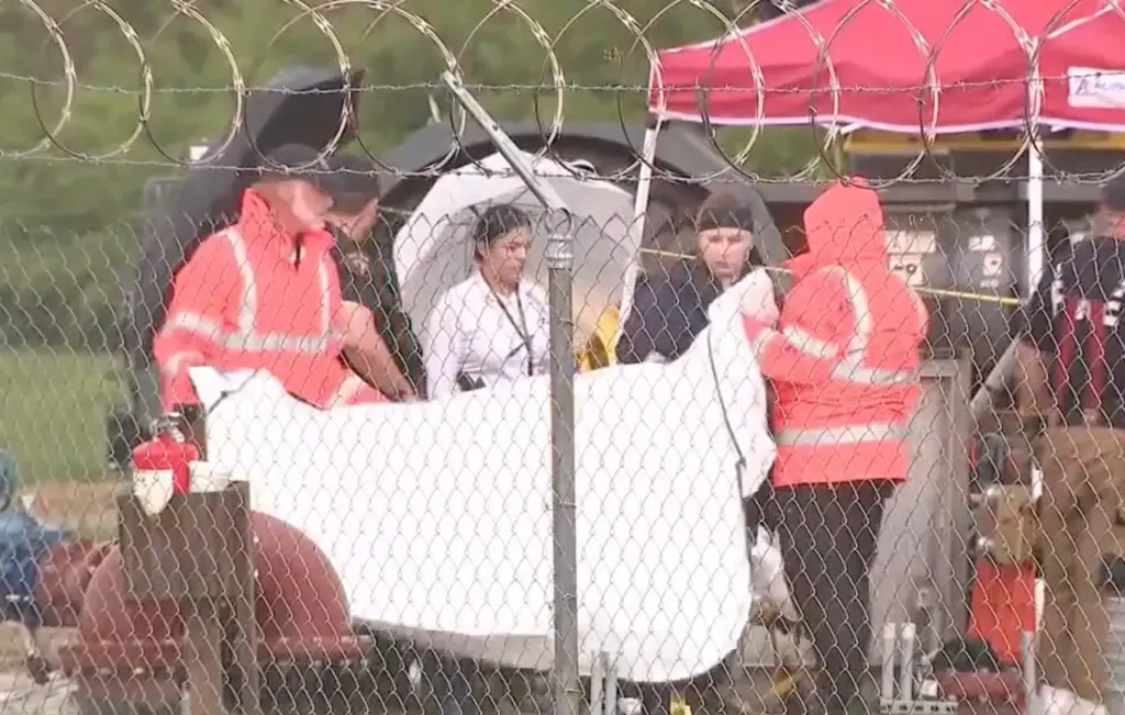 Construction workers behind a chain-link fence at a construction site.