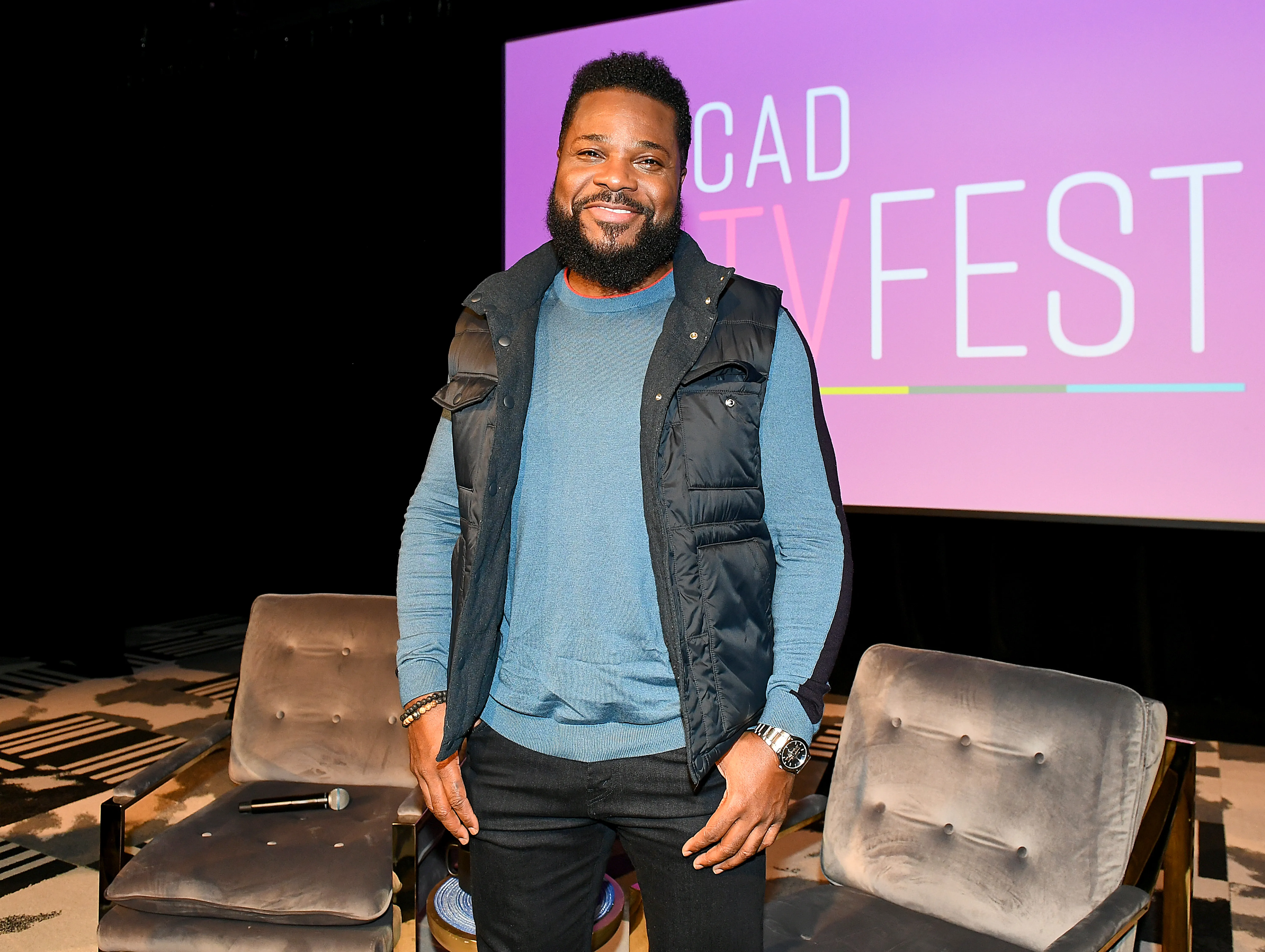 Malcolm-Jamal Warner stands smiling on a stage.