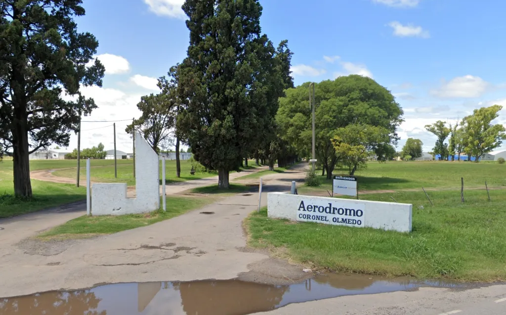 Entrance to Coronel Olmedo airfield with a sign that reads "Aerodromo Coronel Olmedo."